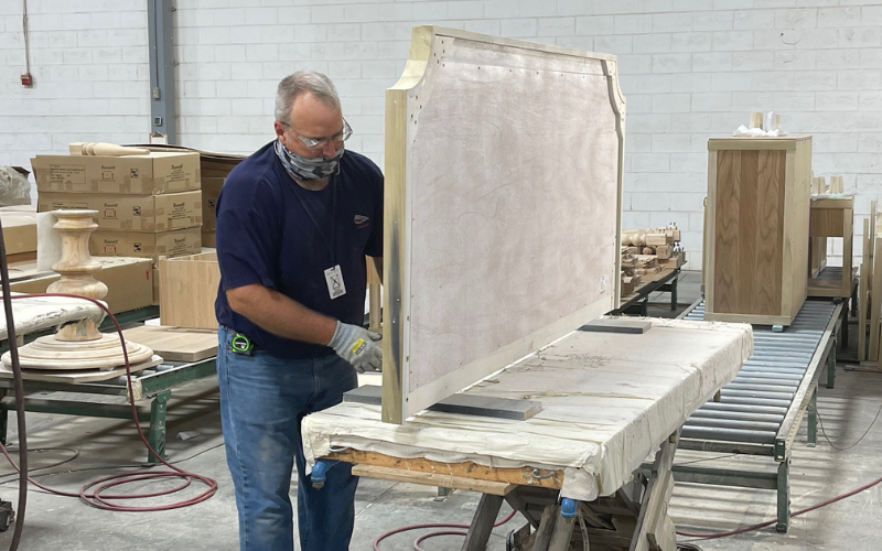 In addition to dining chairs and occasional tables, the Martinsville plant also produces some beds. Here an employee is seen working on an upholstered headboard.