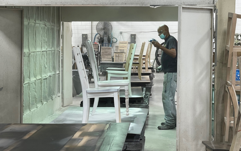 A worker is seen hand finishing a number of chair frames as they come down the line.