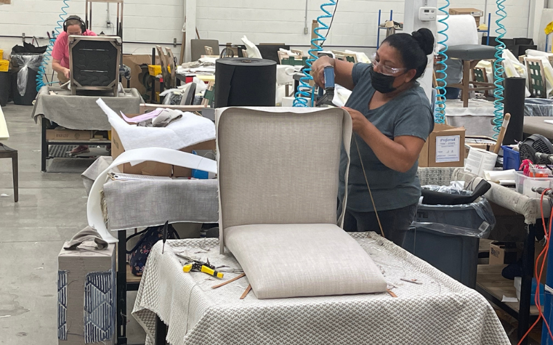 Another employee in Martinsville is seen affixing fabric to a chair frame. The plant produces about 150 dining chairs per day.