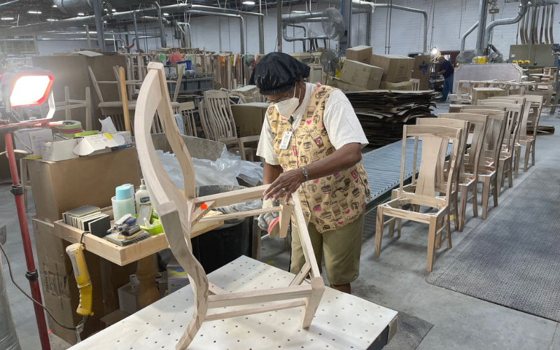 A worker at the Martinsville plant sands a chair frame.