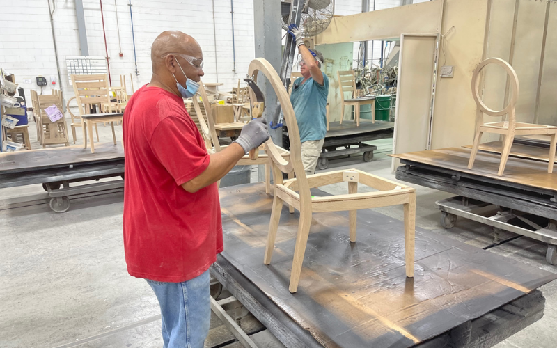 A lot of handwork goes into the production and finishing of dining chair frames. This employee is seen distressing the back of a chair.